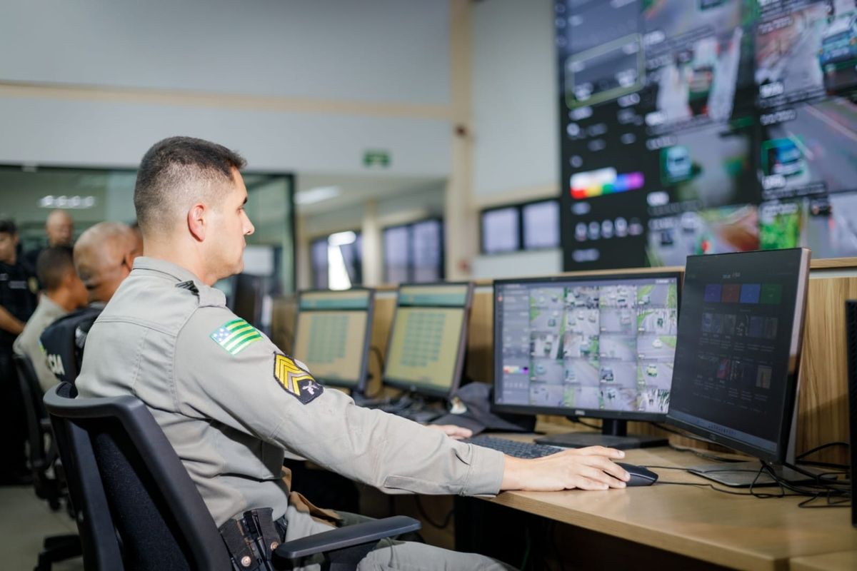 Policial militar opera computador em sala de videomonitoramento