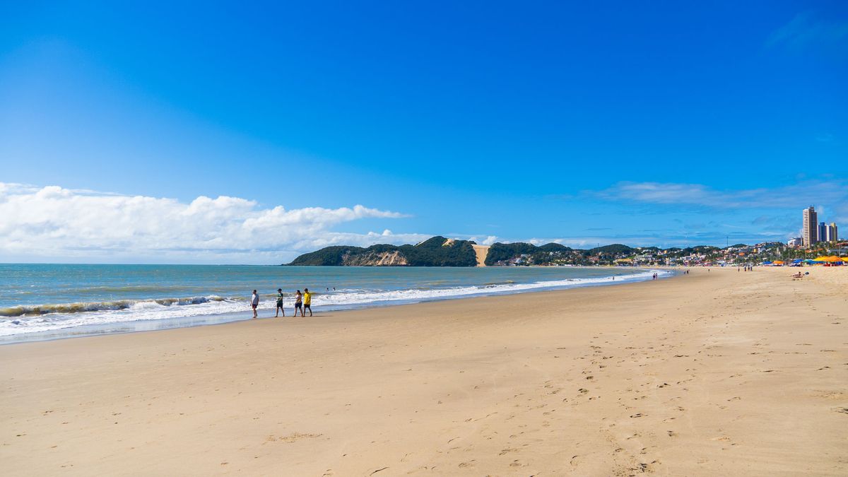 Faixa de areia e mar da praia em frente ao Esmeralda Praia Hotel, com Morro do Careca ao horizonte